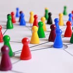 A strategic arrangement of colorful pawns connected on a game board, symbolizing networking and teamwork.