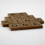 Wooden Scrabble tiles spelling 'Be The Kind One' with focus on words and white background.