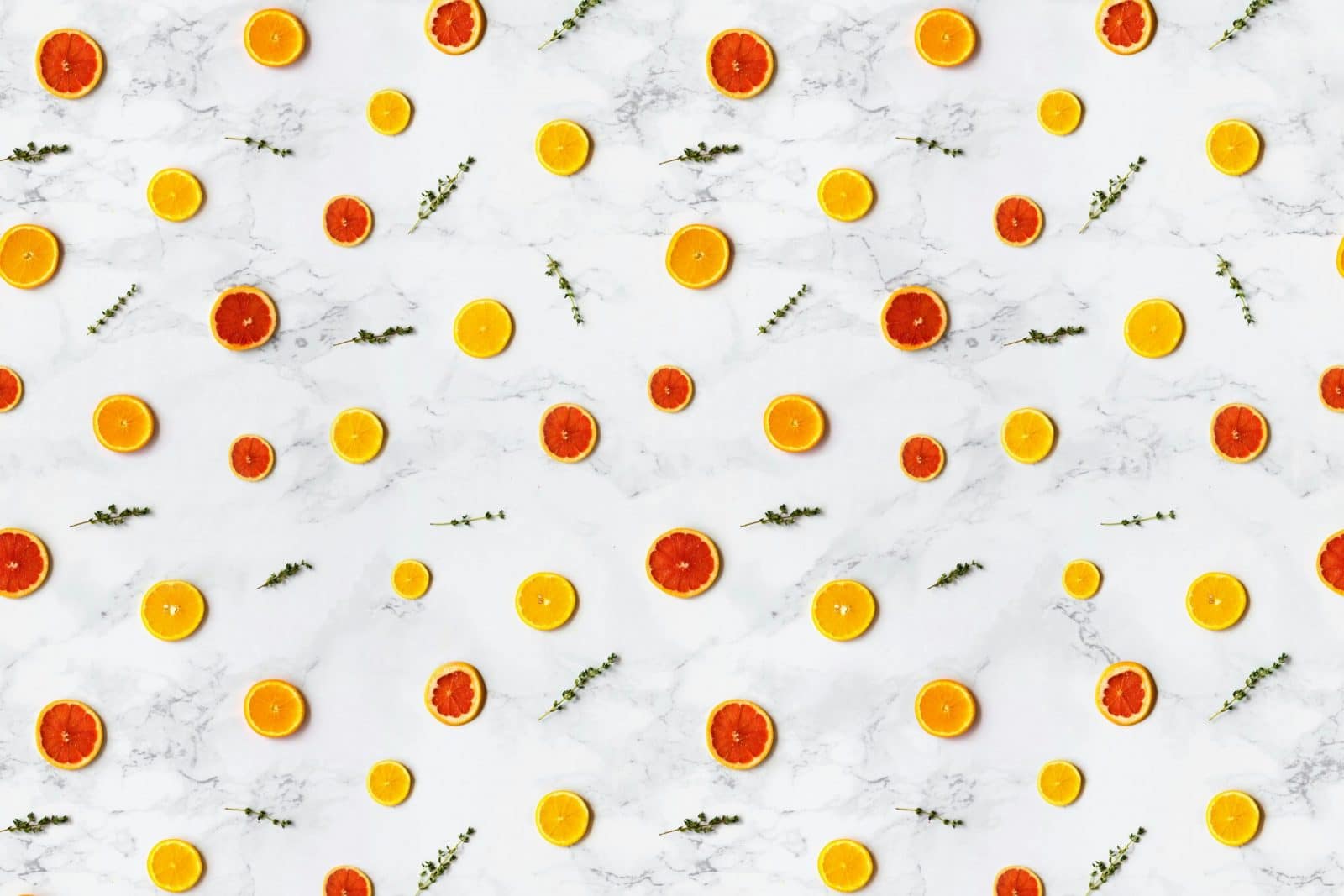 Colorful citrus slices arranged in a flat lay pattern on a marble surface, ideal for backgrounds.
